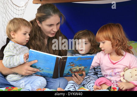 mother reading a book about pirates to her children in a Billi-Bolli loft bed, Stock Photo