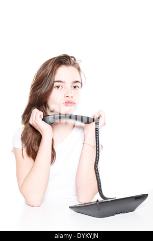 sulking female teenager holding telephone receiver in both hands, isolated on white. Stock Photo