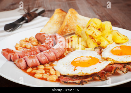 Sausages, beans, beans, ham and egg with toast bread and potatoes. Culinary english eating. Stock Photo