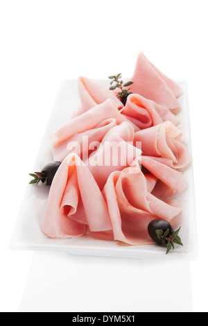 Delicious ham slices with black olives and fresh herbs isolated on white square. Culinary meat eating concept. Stock Photo