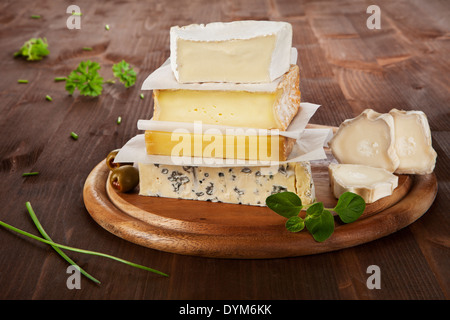 Luxurious cheese variation on wooden board with parsley and chive. Stock Photo