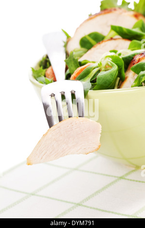 Fresh caesar salad with lettuce, carrot and chicken in bowl, chicken piece on silver fork. Luxurious light summer eating. Stock Photo