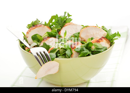 Delicious lamb's lettuce salad with chicken in green bowl, piece of chicken on silver fork. Luxurious healthy summer meal. Stock Photo