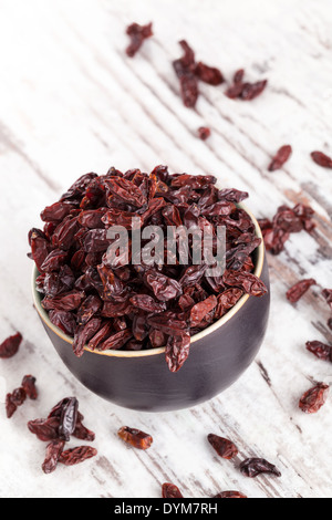 Full bowl of goji on white wooden textured background. Healthy traditional chinese eating supplement. Stock Photo