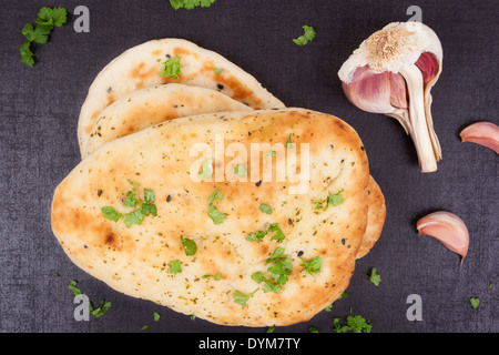 Naan bread with fresh parsley herb and garlic on black background top view. Culinary indian and eastern cuisine. Stock Photo
