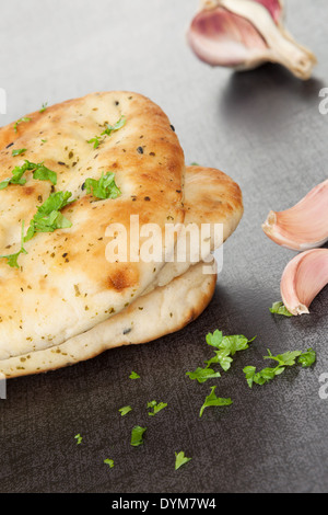 Naan flatbread stack with fresh cilantro herb and garlic on dark black and grey background. Culinary eastern background. Stock Photo