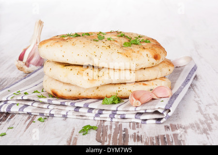 Luxurious naan background. Naan flat bread pile with fresh parsley herb and garlic on white wooden textured background. Stock Photo