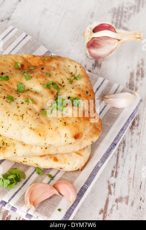 Luxurious naan flatbread background. Naan stack with fresh cilantro and garlic on white wooden textured background. Culinary Stock Photo