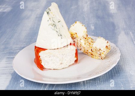 Culinary luxurious cheese plate. Cheese variation on vintage plate on white and blue wooden background. Stock Photo