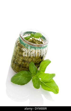 Green basil pesto in glass jar isolated on white background. Healthy vegetarian eating. Stock Photo