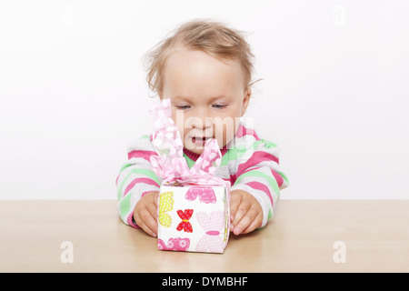 Birthday surprise. Cute baby girl opening present isolated on white background. Stock Photo