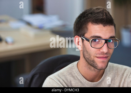 Portrait of a smart an handsome young man in office with available light Stock Photo