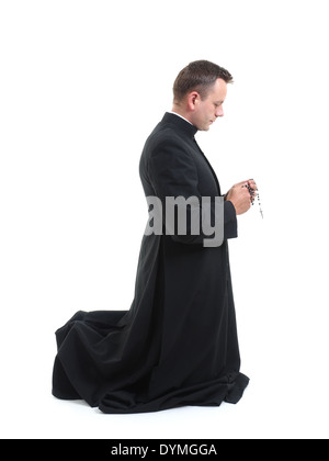 Catholic priest kneeling and saying his rosary beads Stock Photo