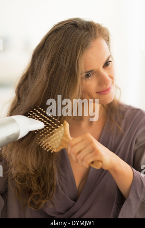 Young woman blow drying hair Stock Photo