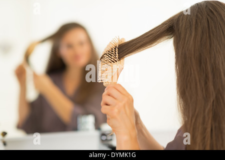 Young woman combing hair in bathroom. rear view Stock Photo