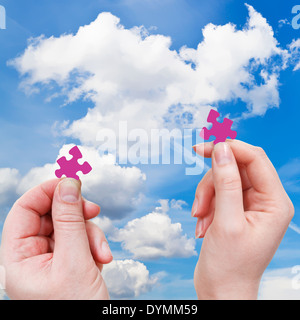 male and female hands with little puzzle pieces with white cloud and blue sky background Stock Photo