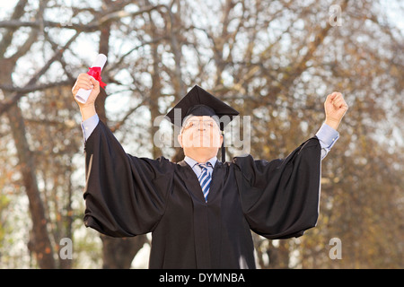 Mature graduate gesturing happiness in park Stock Photo