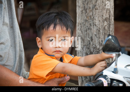 Horizontal portrait of an attractive young boy on the front of a motorbike in Laos. Stock Photo