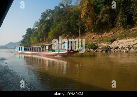 Horizontal view of a Laotian slow boat traveling up the Mekong river on a sunny day. Stock Photo