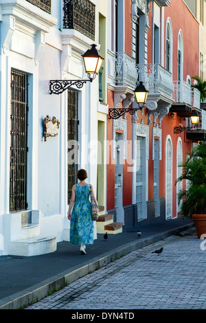 Woman walking by colorful facades and lamps, Old San Juan, Puerto Rico Stock Photo