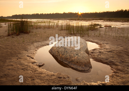 Rock in a pool of water during sunset with very warm unusual light conditions at Singing Sands Bruce Peninsula NP Ontario Canada Stock Photo