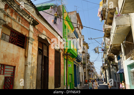 Street scene in Old Havana Cuba with men repairing stucco wall, children playing and women walking Stock Photo