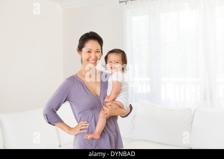 Mother holding baby girl in living room Stock Photo