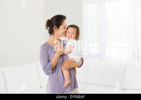 Mother holding baby girl in living room Stock Photo