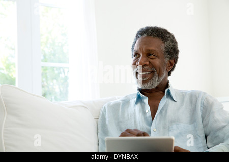 Senior man using digital tablet on sofa Stock Photo