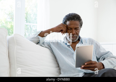 Senior man using digital tablet on sofa Stock Photo