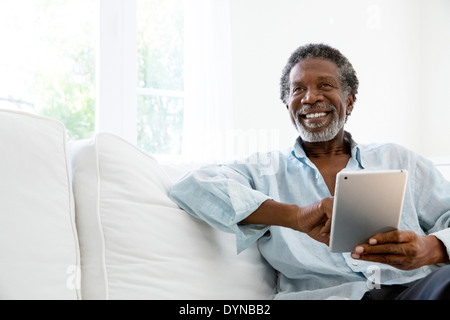 Senior man using digital tablet on sofa Stock Photo