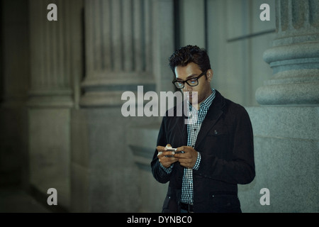 Man using cell phone on city street Stock Photo