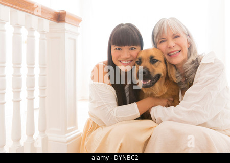 Mother and daughter hugging dog on steps Stock Photo