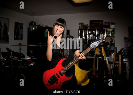 Woman playing electric guitar in basement Stock Photo
