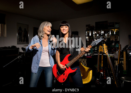 Mother and daughter singing and playing guitar in basement Stock Photo