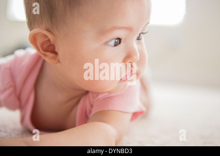 Mixed race baby girl laying on carpet