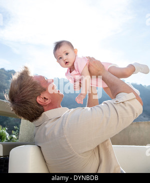 Father holding baby girl on sofa Stock Photo