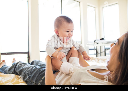 Mother playing with baby girl on bed Stock Photo