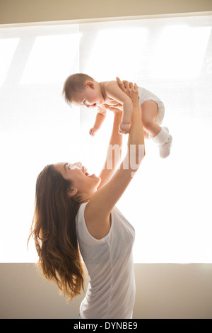 Mother lifting baby girl overhead Stock Photo