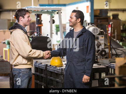 Workers shaking hands in warehouse Stock Photo