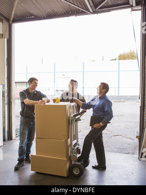 Workers enjoying coffee break at warehouse loading dock Stock Photo