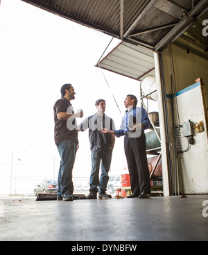 Manager and workers talking at warehouse loading dock Stock Photo