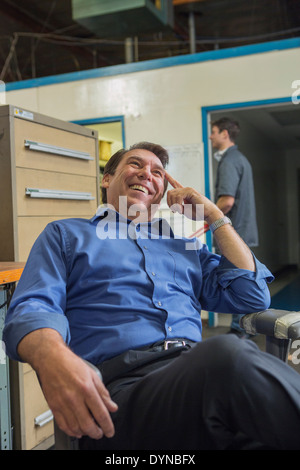 Caucasian manager laughing in warehouse Stock Photo