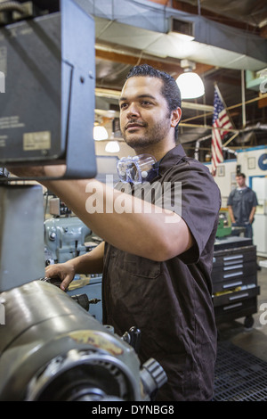 Hispanic worker operating machinery in factory Stock Photo