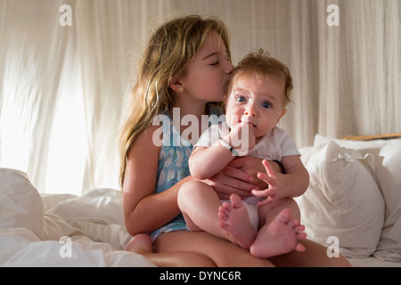 Caucasian girl kissing sibling on sofa Stock Photo