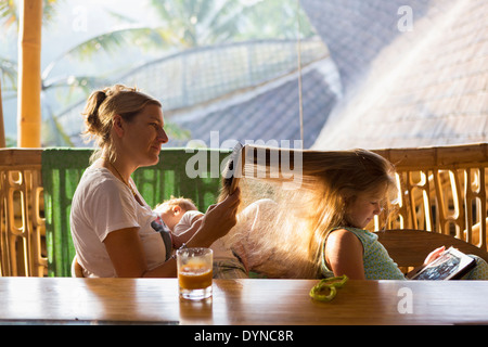Caucasian mother brushing daughter's hair on patio Stock Photo