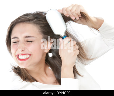 Grimacing woman brushing tangles from hair Stock Photo