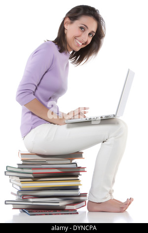 Woman using laptop on stack of books Stock Photo