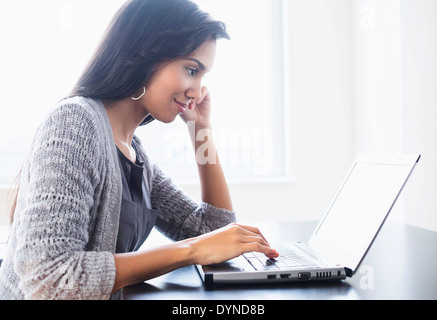 Hispanic woman using laptop on table Stock Photo