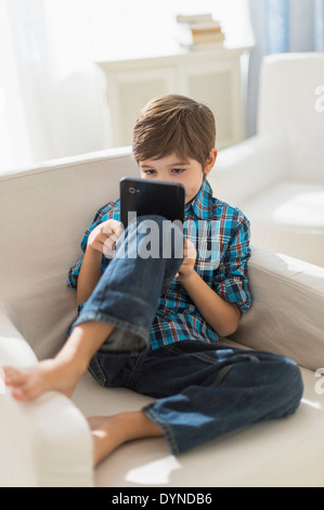 Hispanic boy using digital tablet in armchair Stock Photo